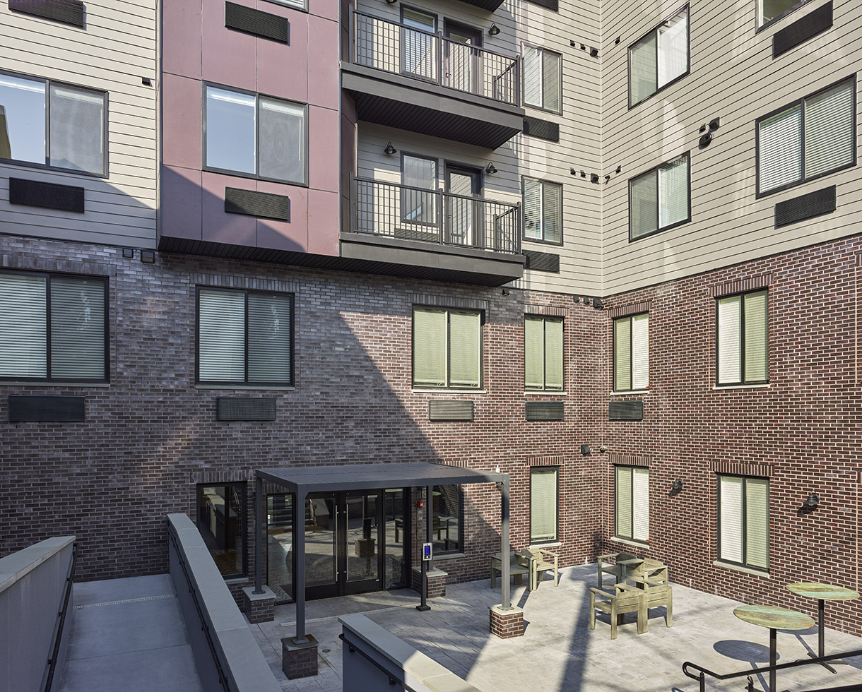 exterior photo of the Aster's courtyard, built into the basement level. apartment balconies can be seen overlooking the space
