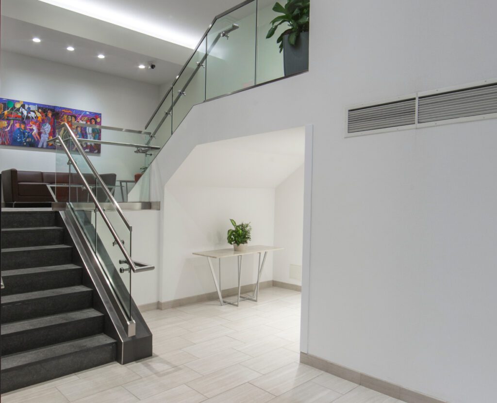 Stairs leading to the upper floor, with a sofa situated between the floors and a large painting hanging on the wall behind it.