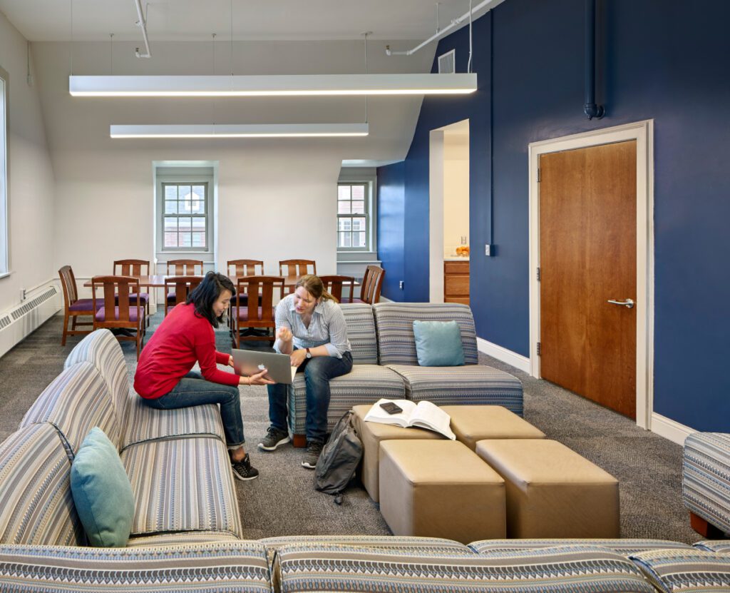 Rutgers Uni common area with two women discussing sitting on chairs
