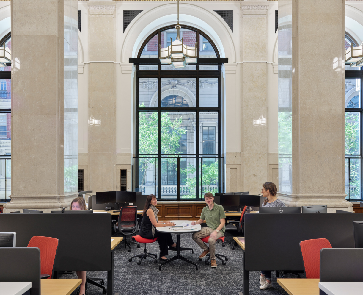 People are sitting at desks, talking to each other at the office area.
