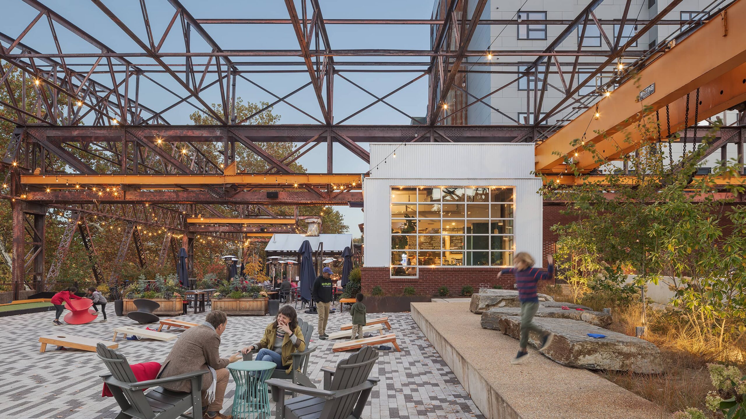 Outdoor patio with sitting area and people are talking to each other and kids are playing
