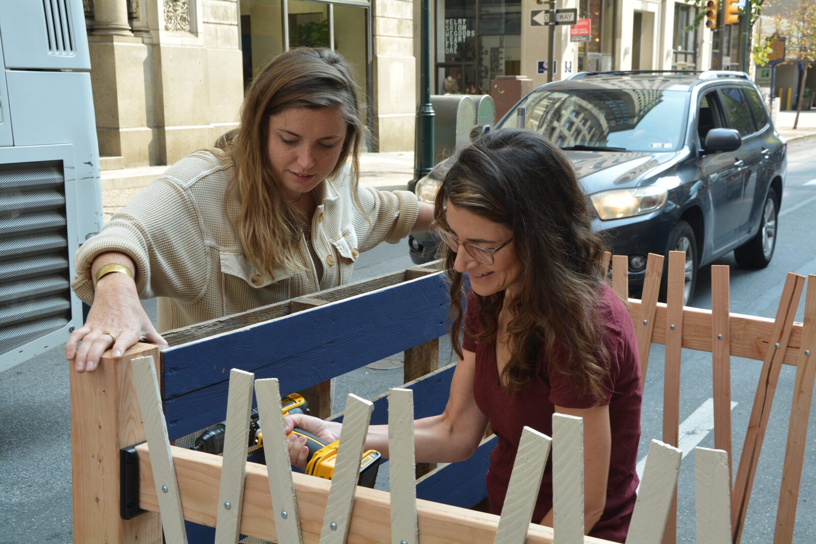 Two CMA employees use power tools to build a structure for AIA Parking Day
